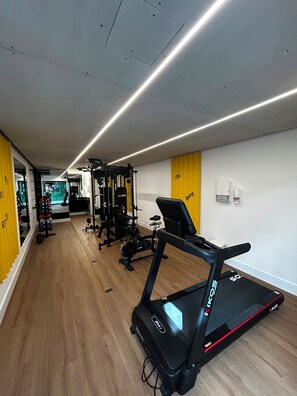 Academia com equipamentos de cardio, máquinas de peso e esteira.