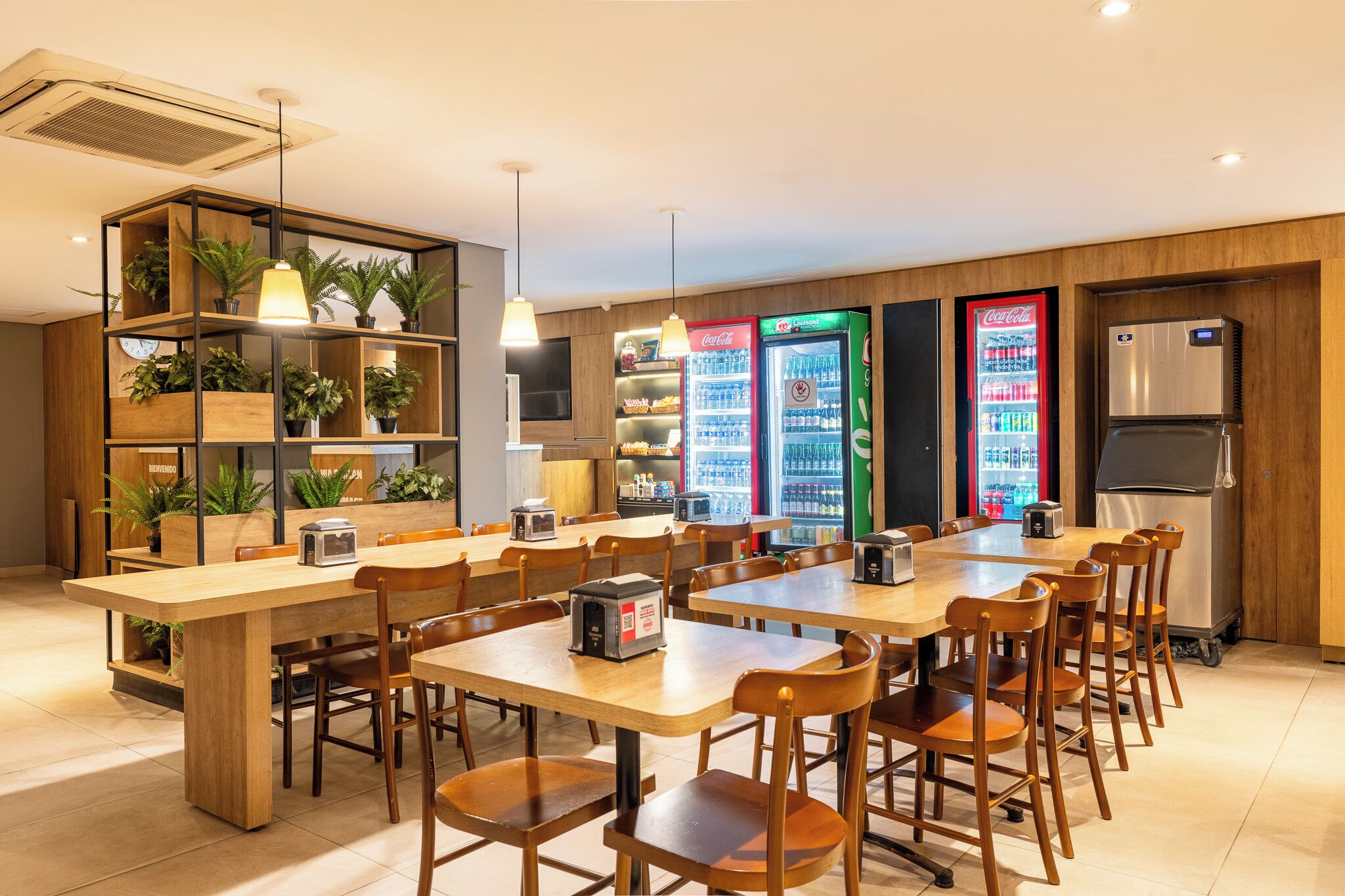 A modern café with wooden furniture, multiple seating areas, and vending machines.