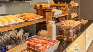 A buffet setup with various food items and condiments. - Uniclass Hotel Lapa (São Paulo)