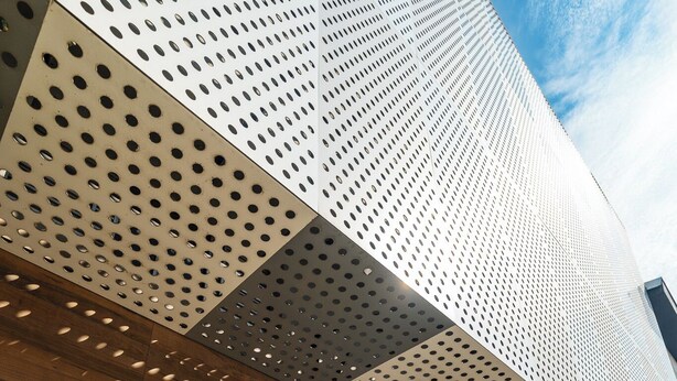 A modern building with a perforated metal facade, a sign reading "UNIQLASS," and a landscaped area with plants. - Uniclass Hotel Lapa (São Paulo)