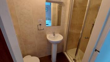 Un baño con inodoro, lavamanos y cabina de ducha de vidrio.