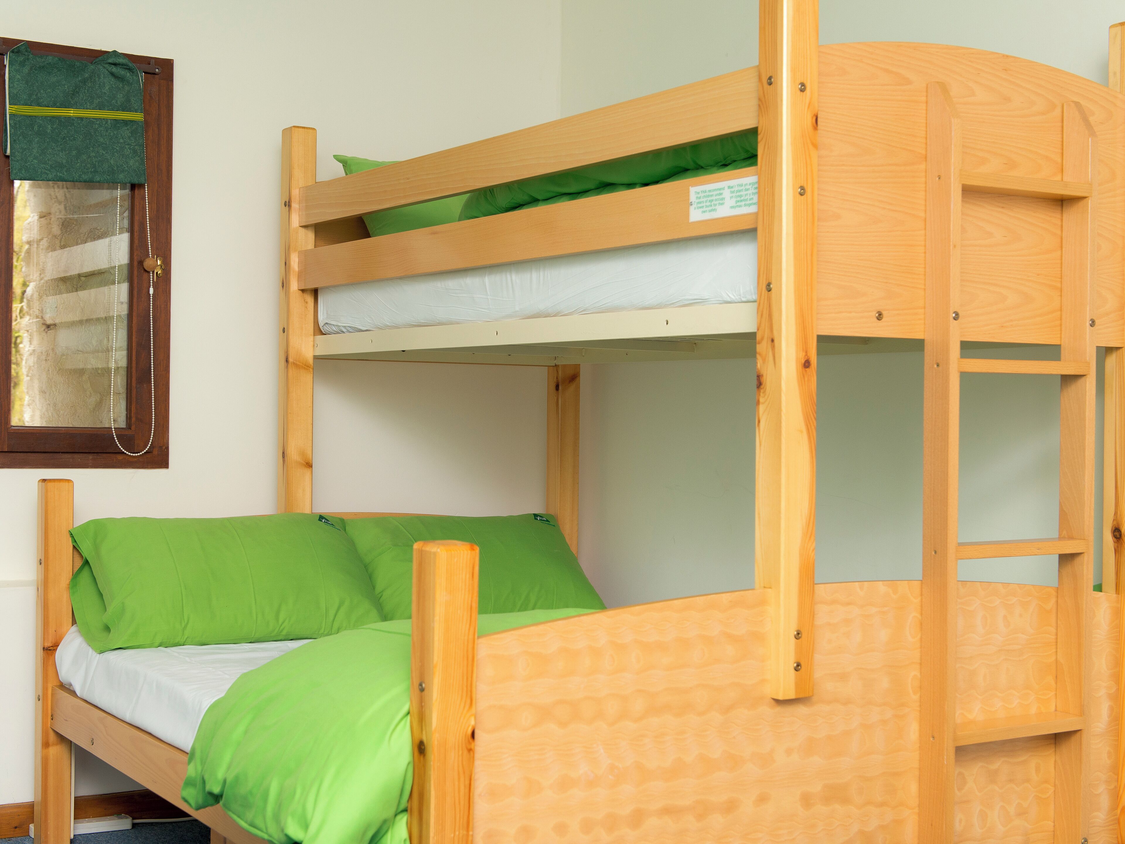 A bunk bed with green bedding and a wooden headboard.