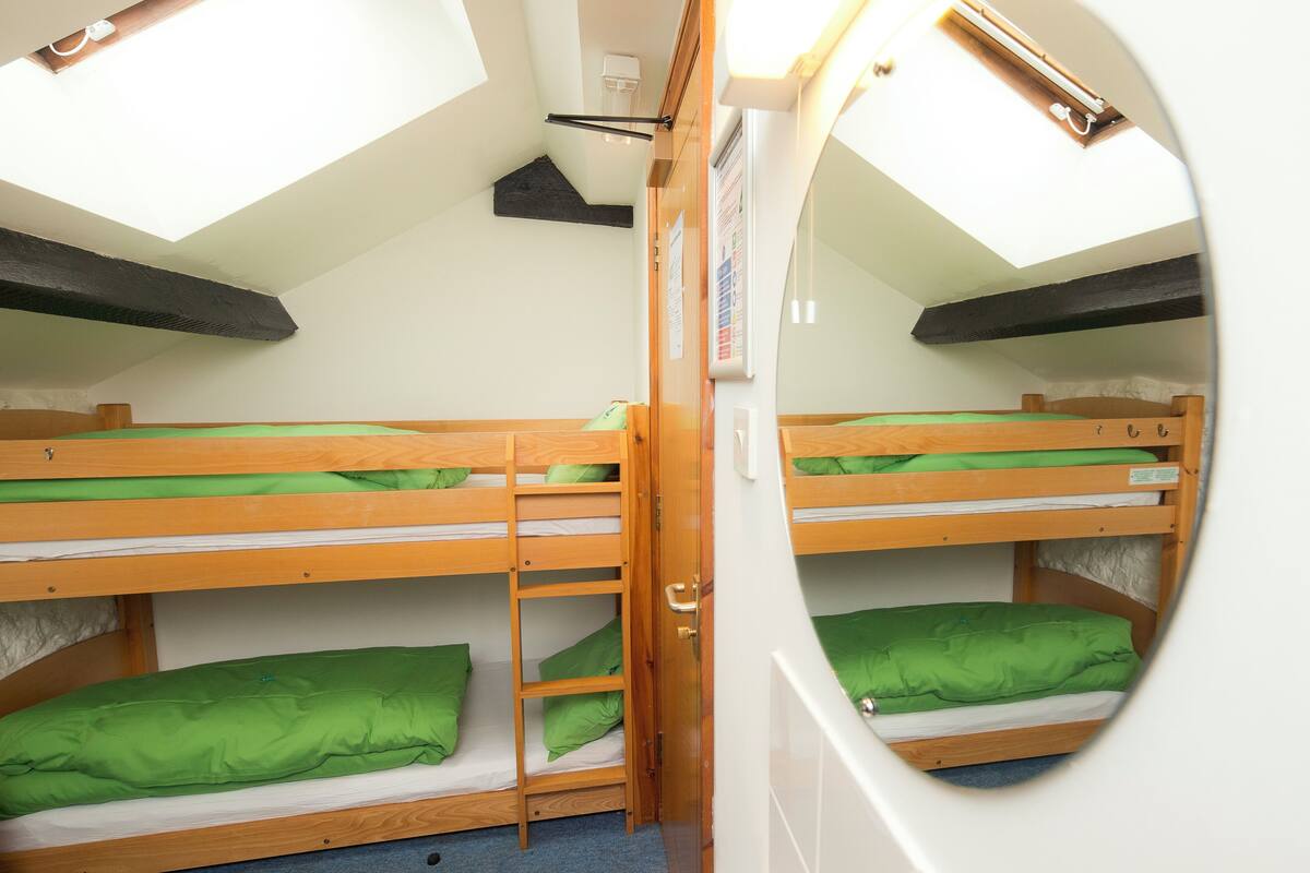 A compact room with two bunk beds, a skylight, and a small window.