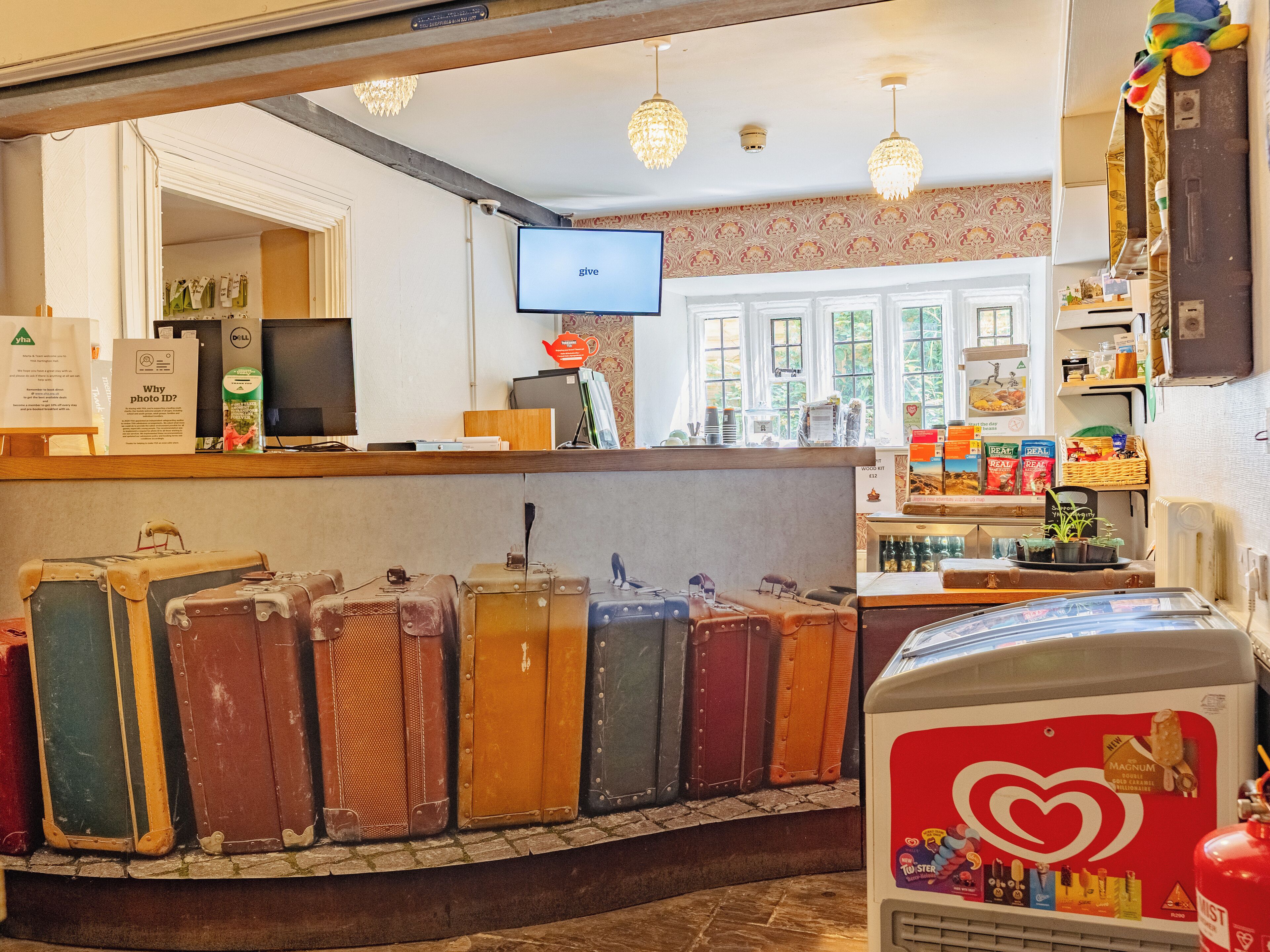 Een receptiegedeelte met vintage koffers, een televisie en diverse spullen op planken.