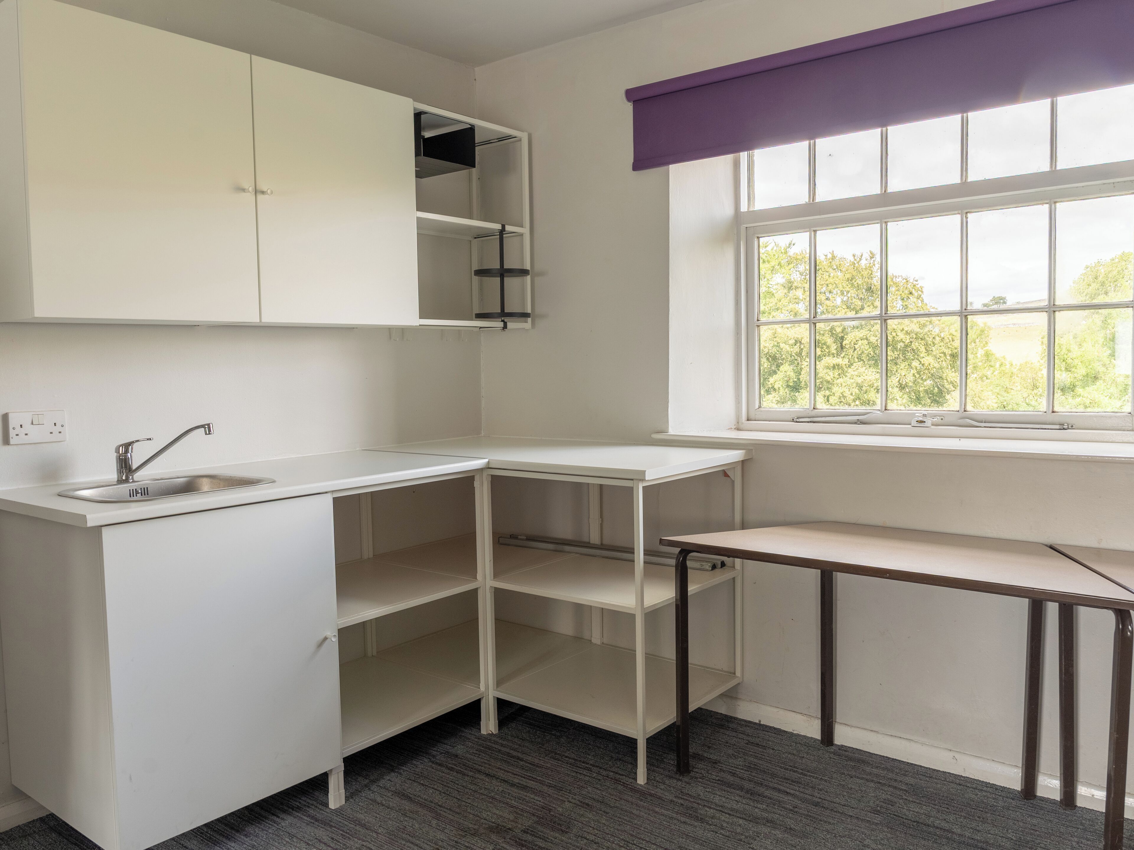 Een moderne keuken met witte kasten, een inbouwspoelbak en een raam met uitzicht op groen.