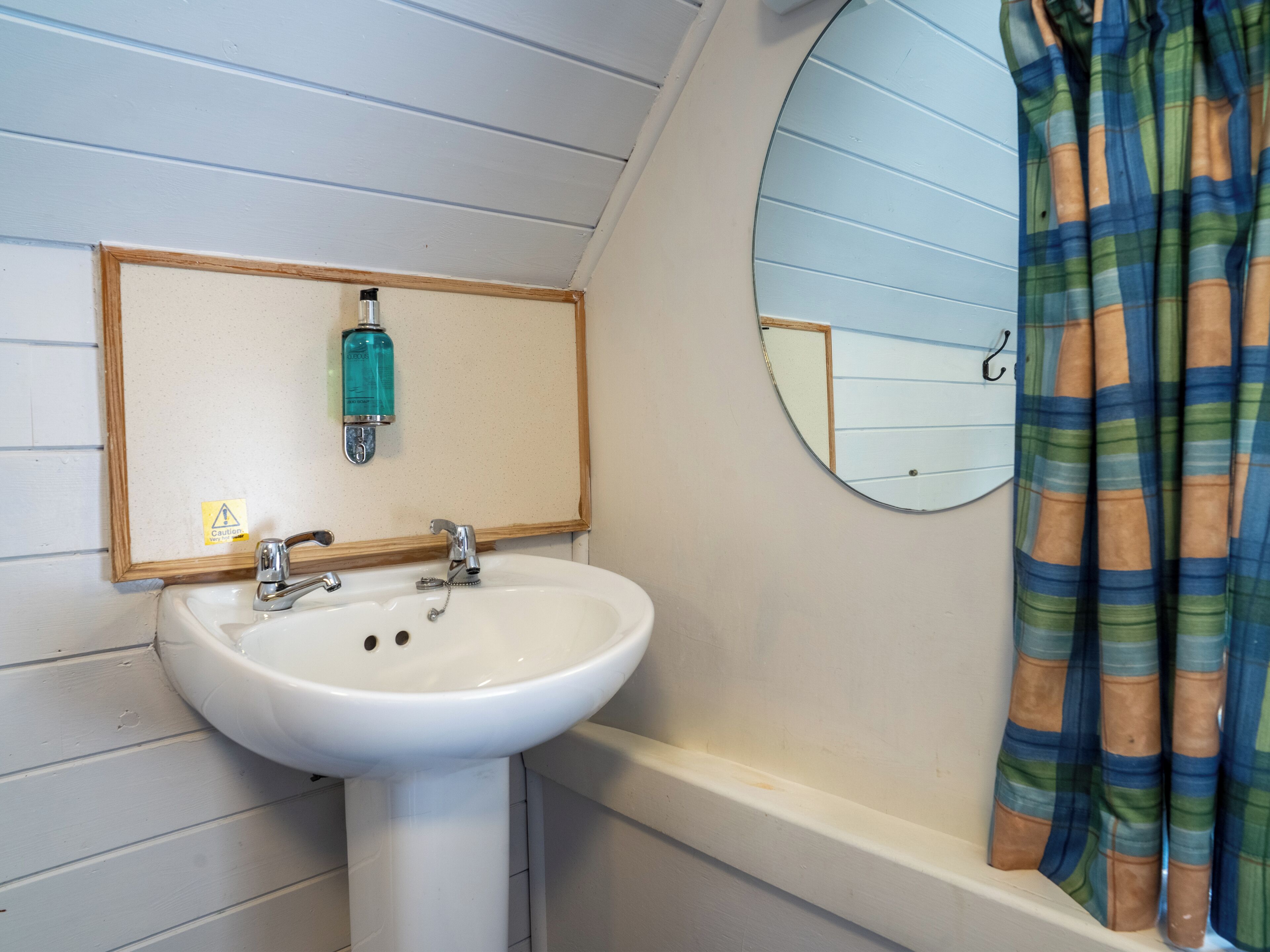 Un baño con lavamanos blanco, un espejo y una cortina de ducha.