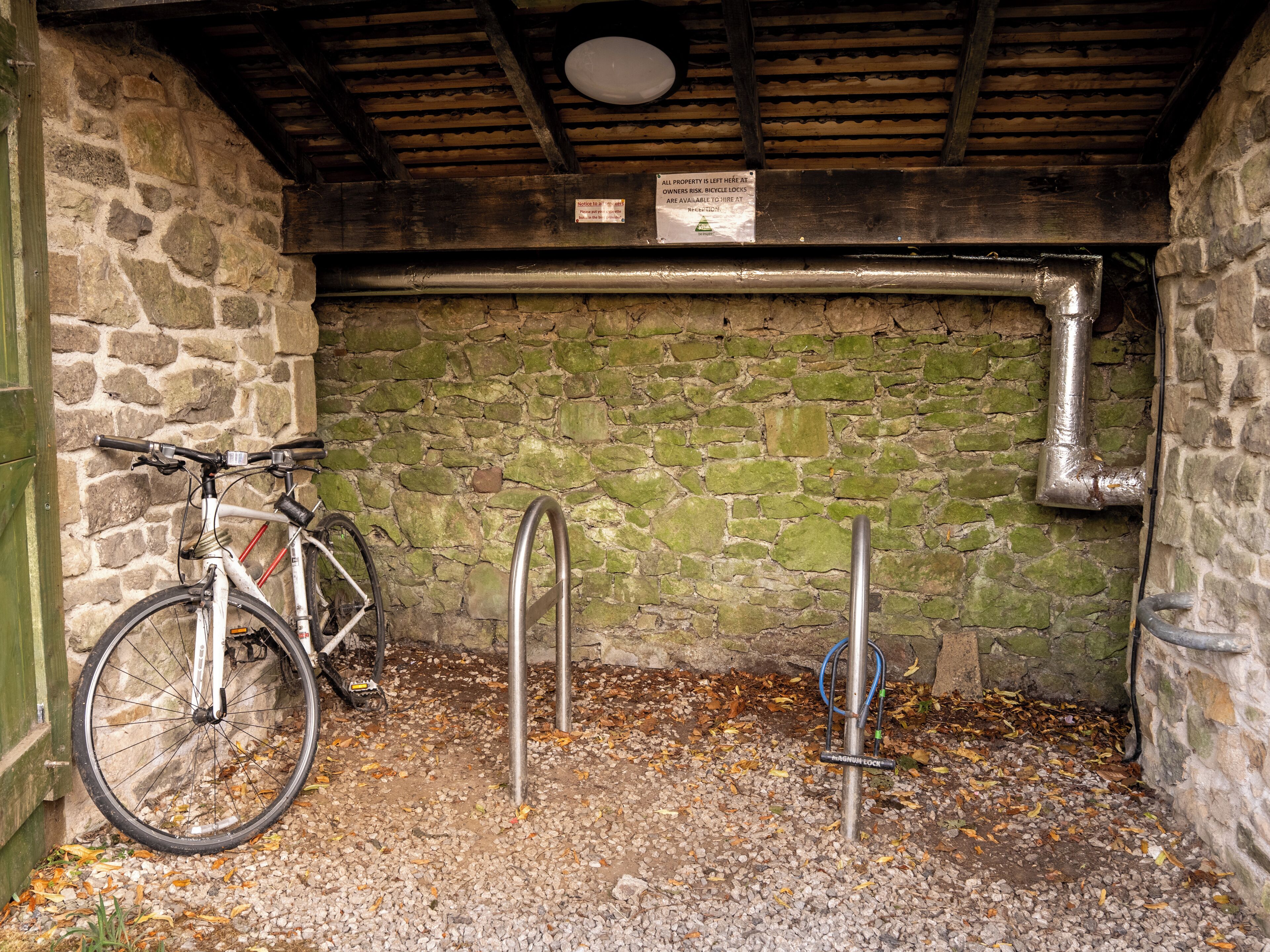 Un mur de pierres avec un vélo et un antivol métallique pour vélo.