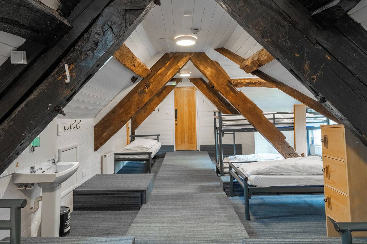 A dormitory with bunk beds, a sink, and a wooden door.