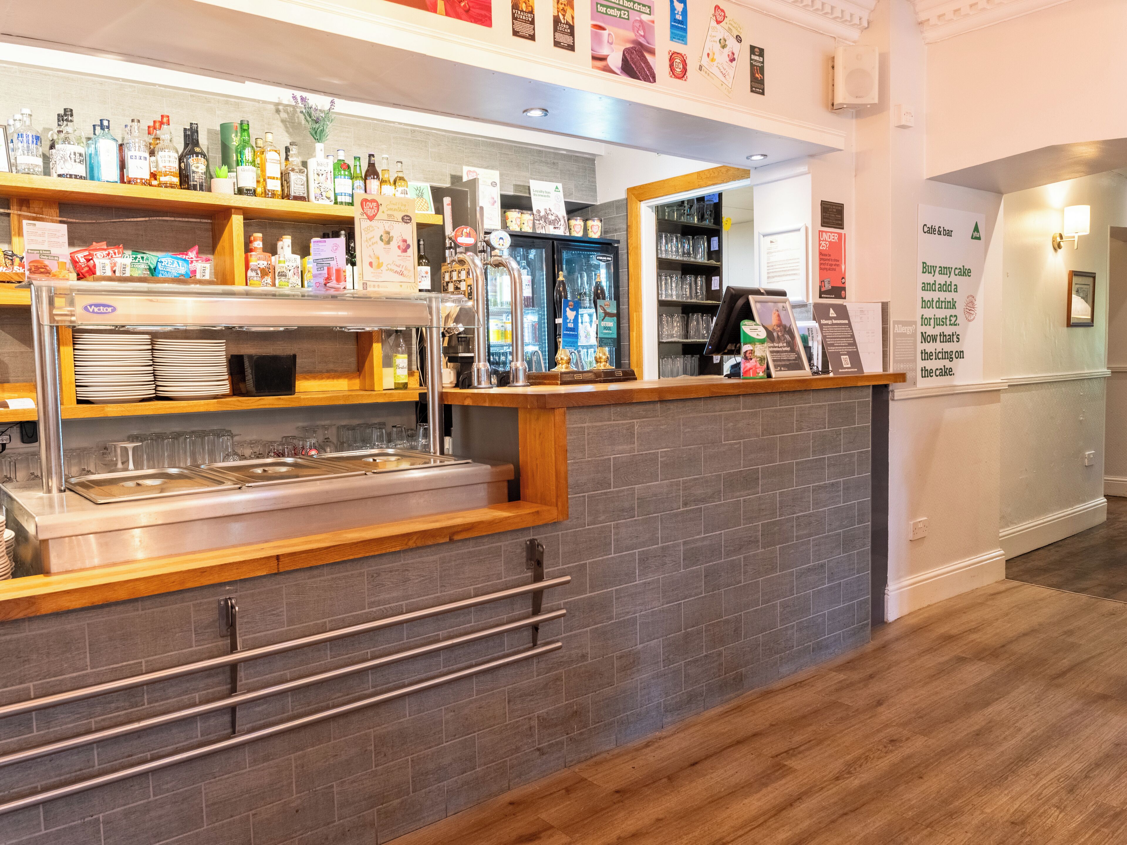 Un espace bar avec un comptoir, des étagères remplies de bouteilles et de verres, et un tableau affichant le menu.