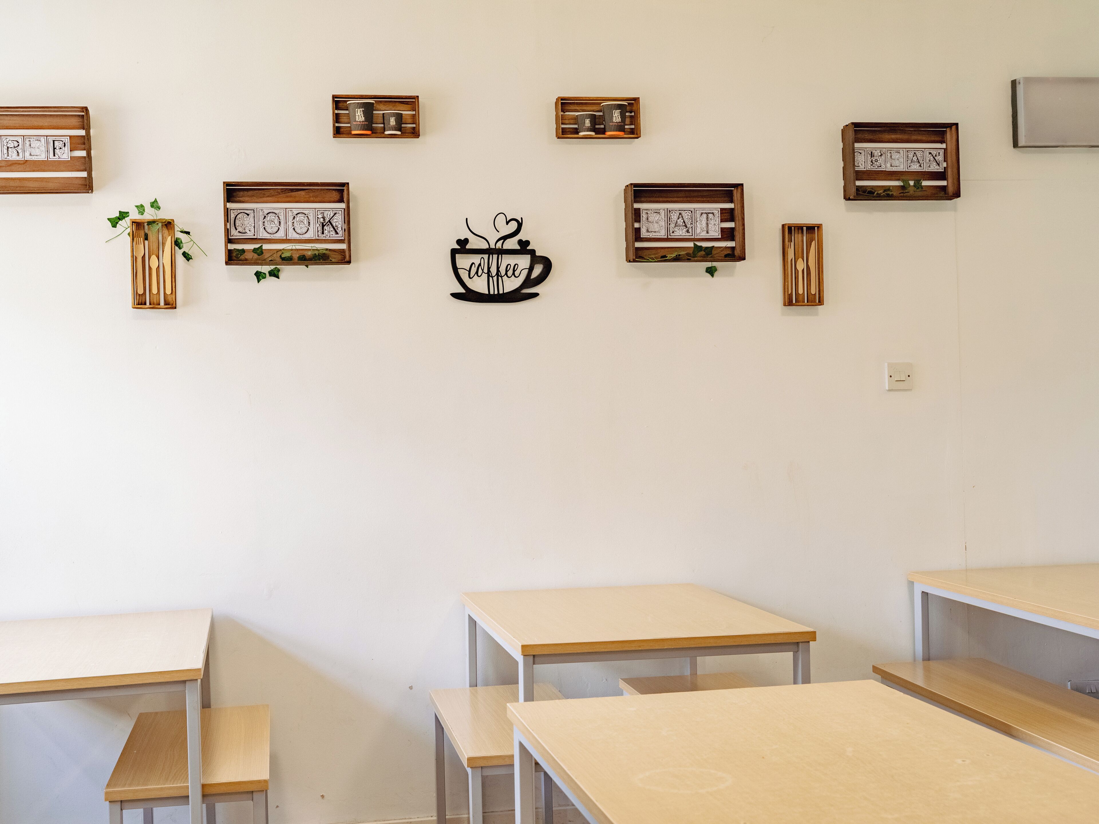 A classroom with wooden desks and educational decorations on the wall.