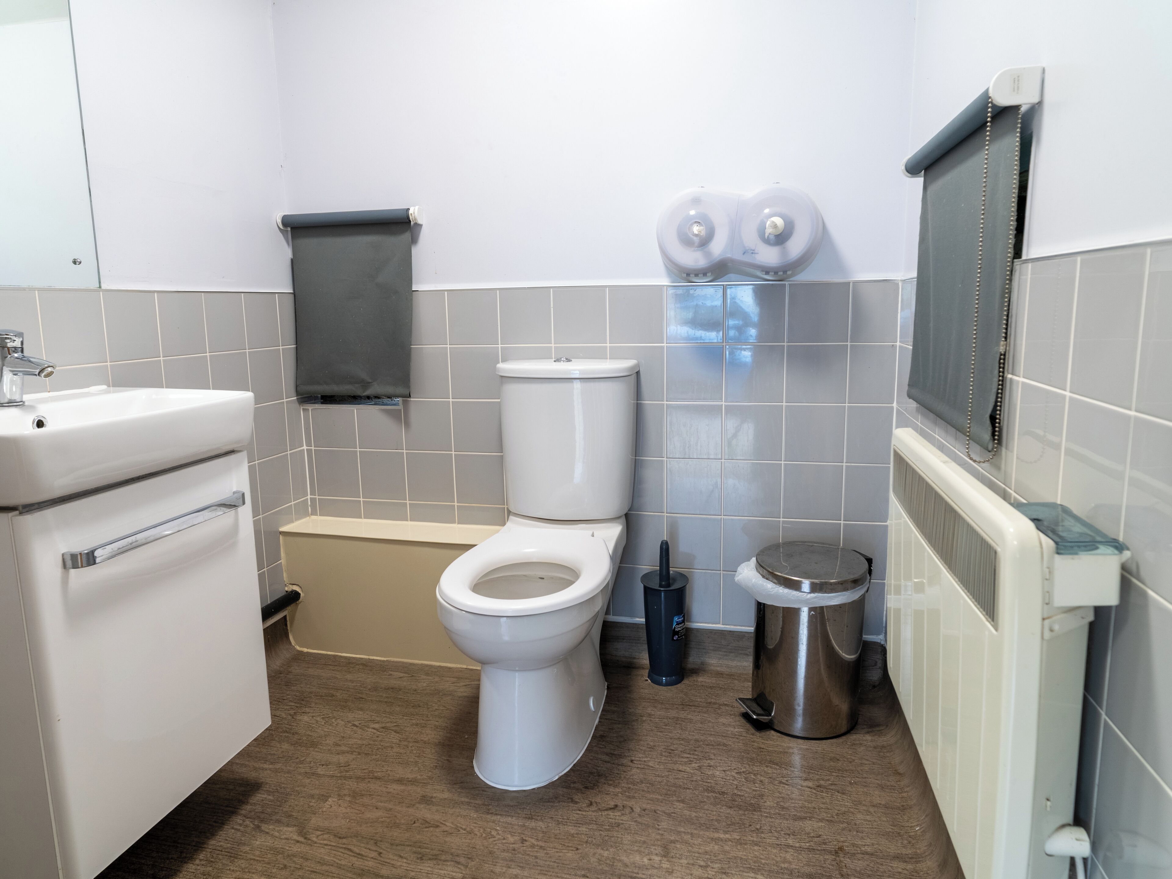 Un baño con inodoro, bidé, lavamanos y un cubo de basura.