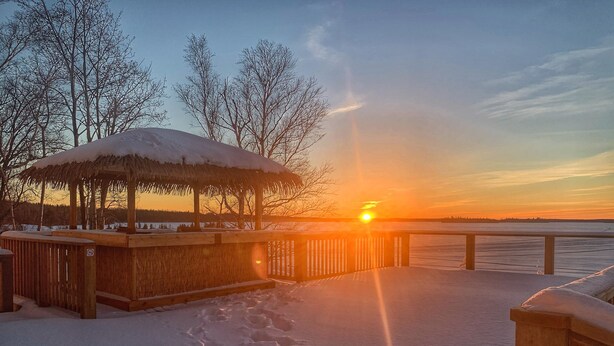 A wooden pier extending over a frozen lake with a thatched gazebo at the end. - Pickle Lake Hotel (Pickle Lake)