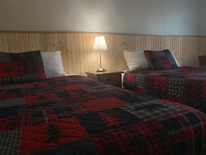 A room with two beds, a nightstand, and a lamp. - Pickle Lake Hotel (Pickle Lake)
