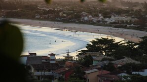 Un pueblo costero con playa, casas y una vista despejada del mar.