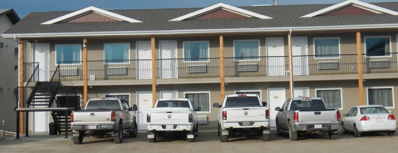 Un motel composé d’un bâtiment à deux étages, doté de nombreux espaces de stationnement et d’un escalier menant à l’étage supérieur.