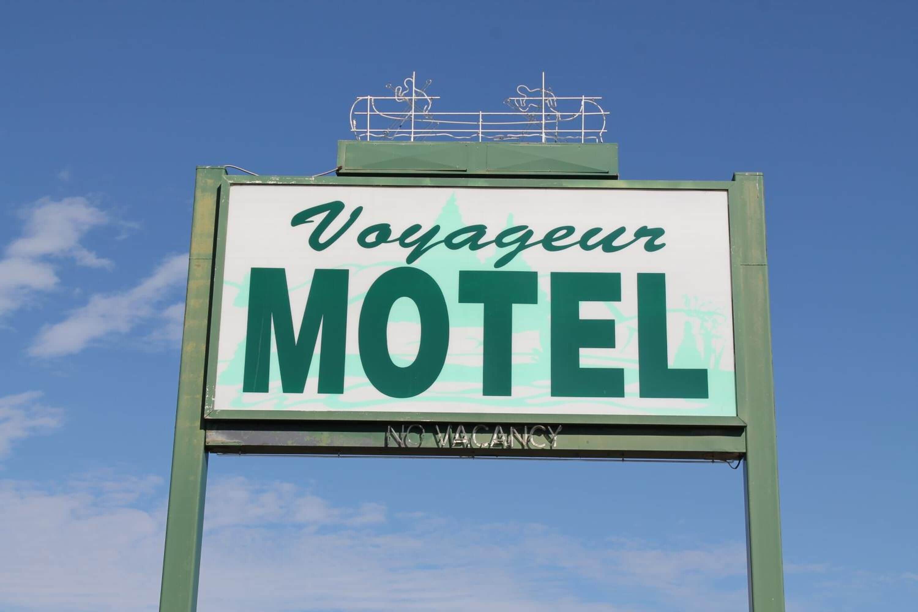 A sign for a motel with the name "Voyageur" and a "NO VACANCY" message.