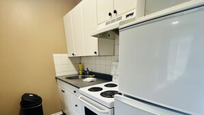 Une cuisine de taille réduite, avec des meubles blancs, une cuisinière et un réfrigérateur.