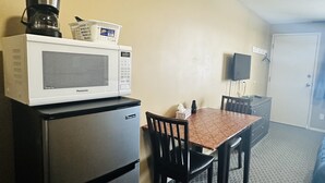 Une petite cuisine équipée d’un four à micro-ondes, d’un réfrigérateur et d’une petite table avec des chaises.