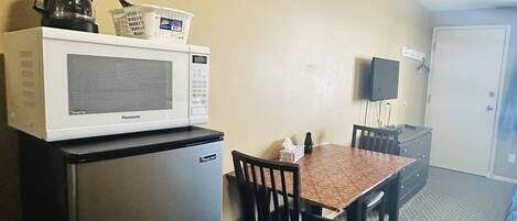 Une petite cuisine équipée d’un four à micro-ondes, d’un réfrigérateur et d’une petite table avec des chaises.