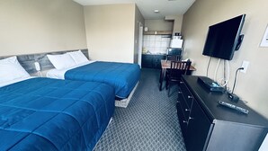 Une chambre d’hôtel avec deux lits, un bureau, une télévision et une kitchenette.