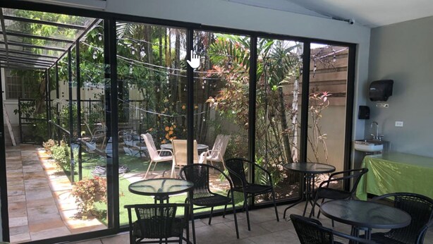 A spacious patio with a glass door leading to a garden, furnished with outdoor chairs and tables. - Palms Hotel Trinidad (Arouca)
