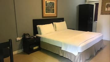A hotel room with a bed, a nightstand with a phone, a framed picture on the wall, and a wardrobe.