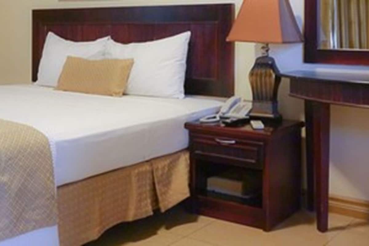 A hotel room with a bed, a bedside table with a lamp, and a telephone.