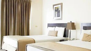 A hotel room with two beds, a nightstand, a lamp, and a framed picture on the wall. - Palms Hotel Trinidad (Arouca)