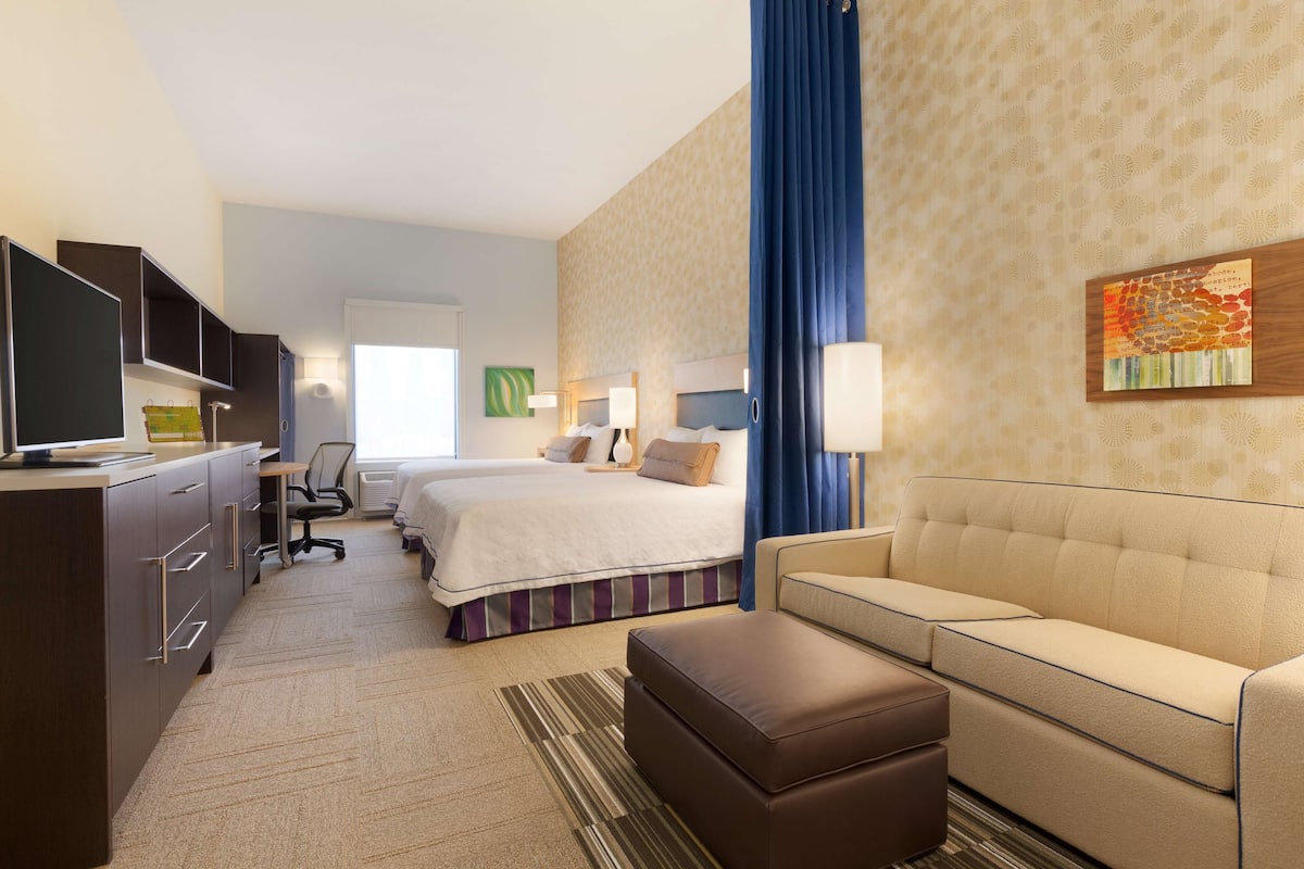Une chambre d’hôtel équipée d’un lit, d’un canapé, d’un bureau avec un ordinateur, d’une chaise et d ’une télévision.