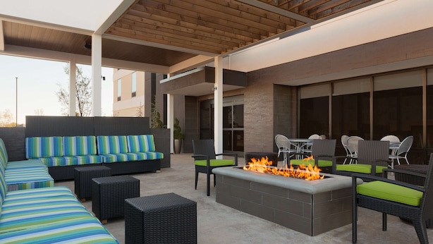 Eine Außenpatio mit Feuerstelle, Sofas und Sesseln.