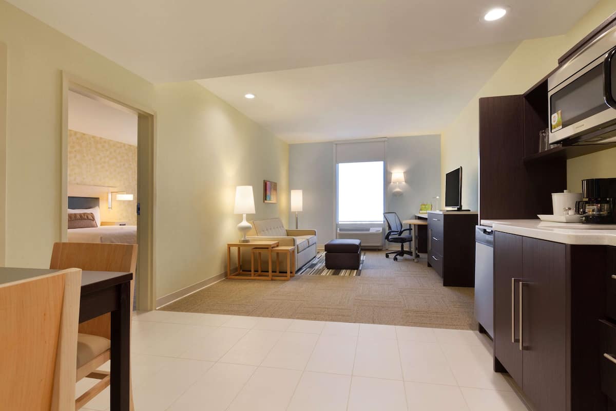 Une chambre d’hôtel moderne dotée d’une kitchenette, d’un coin repas et d’un espace de vie.