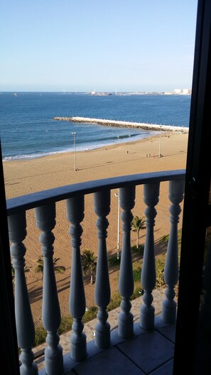 A beach view from a balcony with a railing, a sandy shore, and the ocean. - Hotel Flat Classic (Fortaleza)