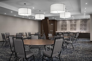 Une salle de conférence équipée d’une table ronde, de plusieurs chaises et de luminaires suspendus.