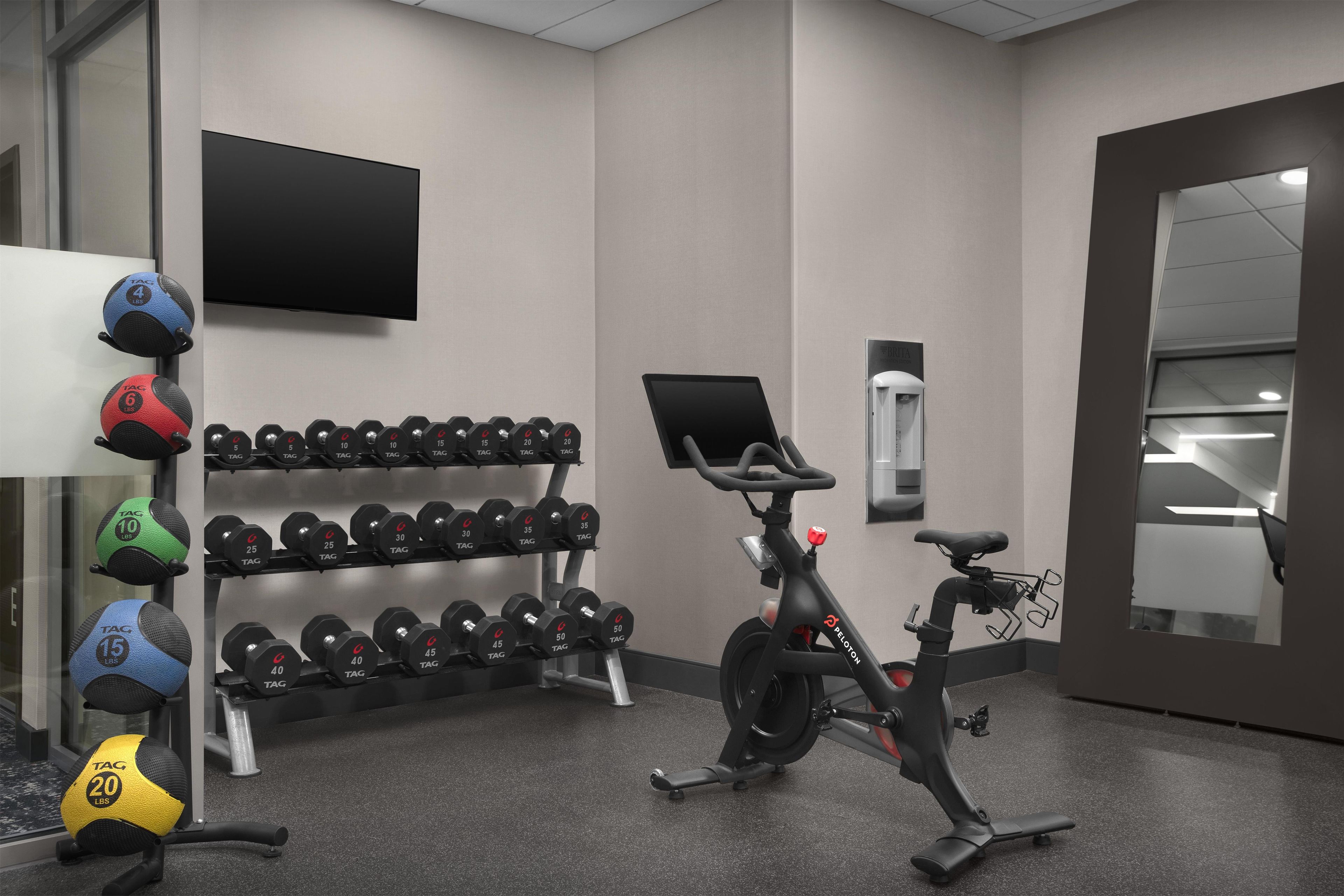 A gym with exercise equipment, a stationary bike, and a television.