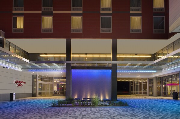 Een hotel lobby met een grote waterpartij, glazen balustrades en een bord met Hampton Inn.