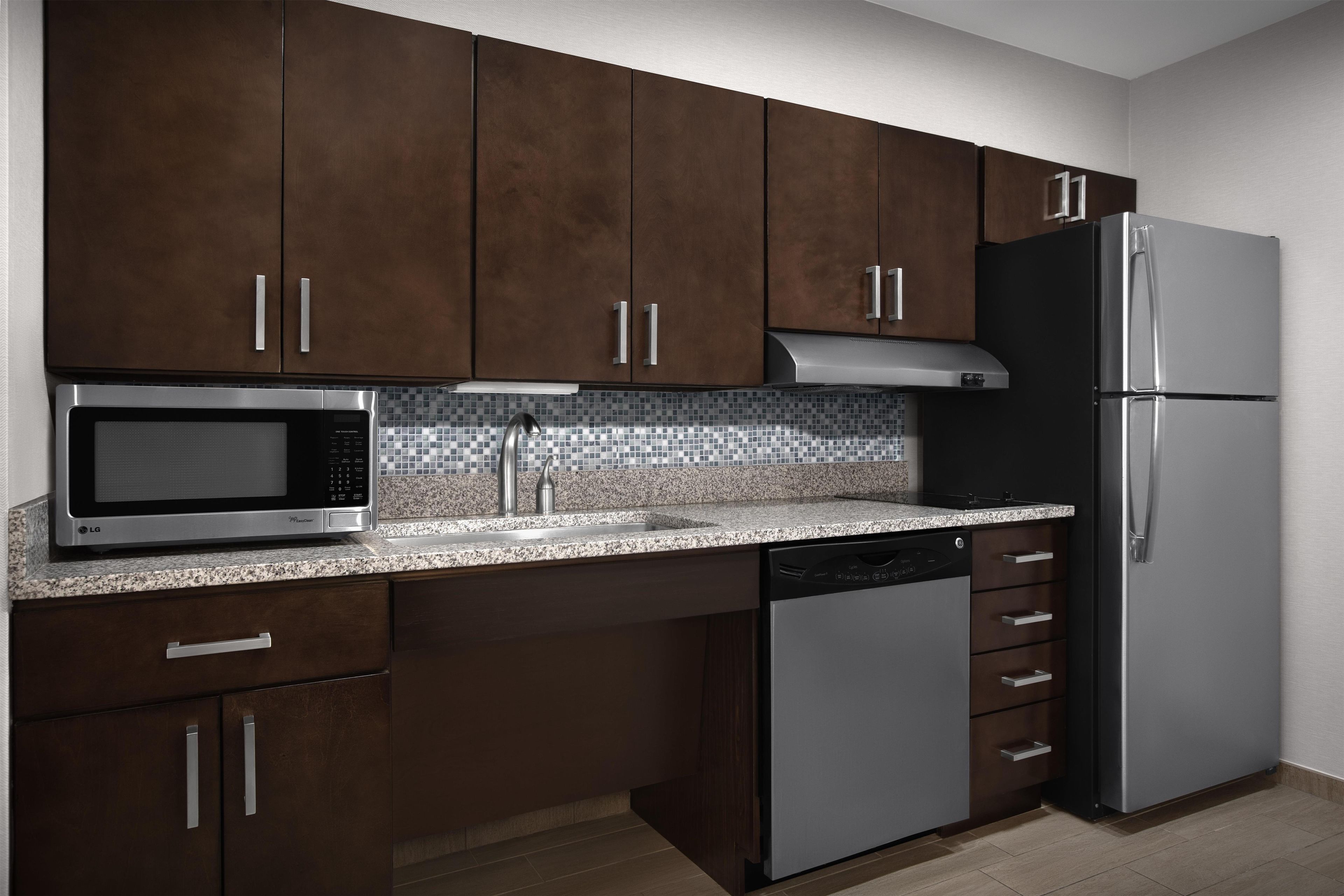 Una cocina moderna con gabinetes de madera oscura, electrodomésticos de acero inoxidable y un salpicadero de azulejos.