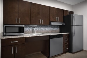 Eine moderne Küche mit dunklen Holzausziehtüren, Edelstahlgeräten und einer gefliesten Spritzschutzwand.