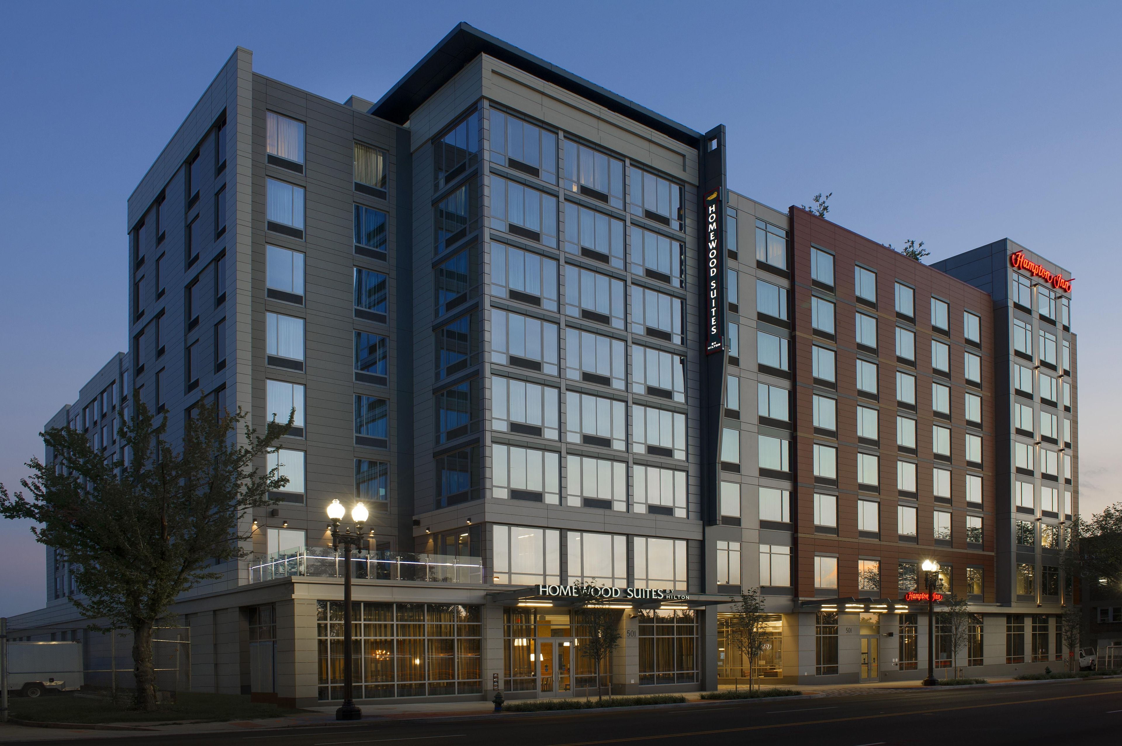 A multi-story hotel with a modern facade, large windows, and a prominent sign for Hampton Inn.