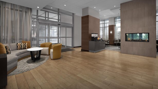 Eine moderne Lobby mit einer Couch, Sesseln, einem kleinen Tisch, einem Kamin und einem Fernseher.