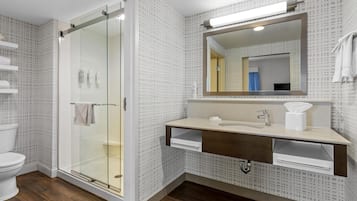 A modern bathroom with a glass shower enclosure, a sink with a mirror, and a toilet.