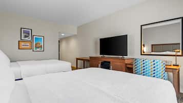 Une chambre d’hôtel avec un lit, un bureau, une télévision et des tableaux encadrés au mur.