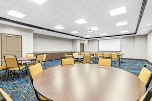 Une salle de conférence dotée d’une grande table ovale entourée de chaises, d’un écran de projection et d’une porte.