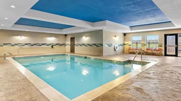 A swimming pool with a tiled edge, a metal ladder, and a ceiling with a blue accent.