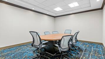 A conference room with a round table, six chairs, and a carpeted floor.