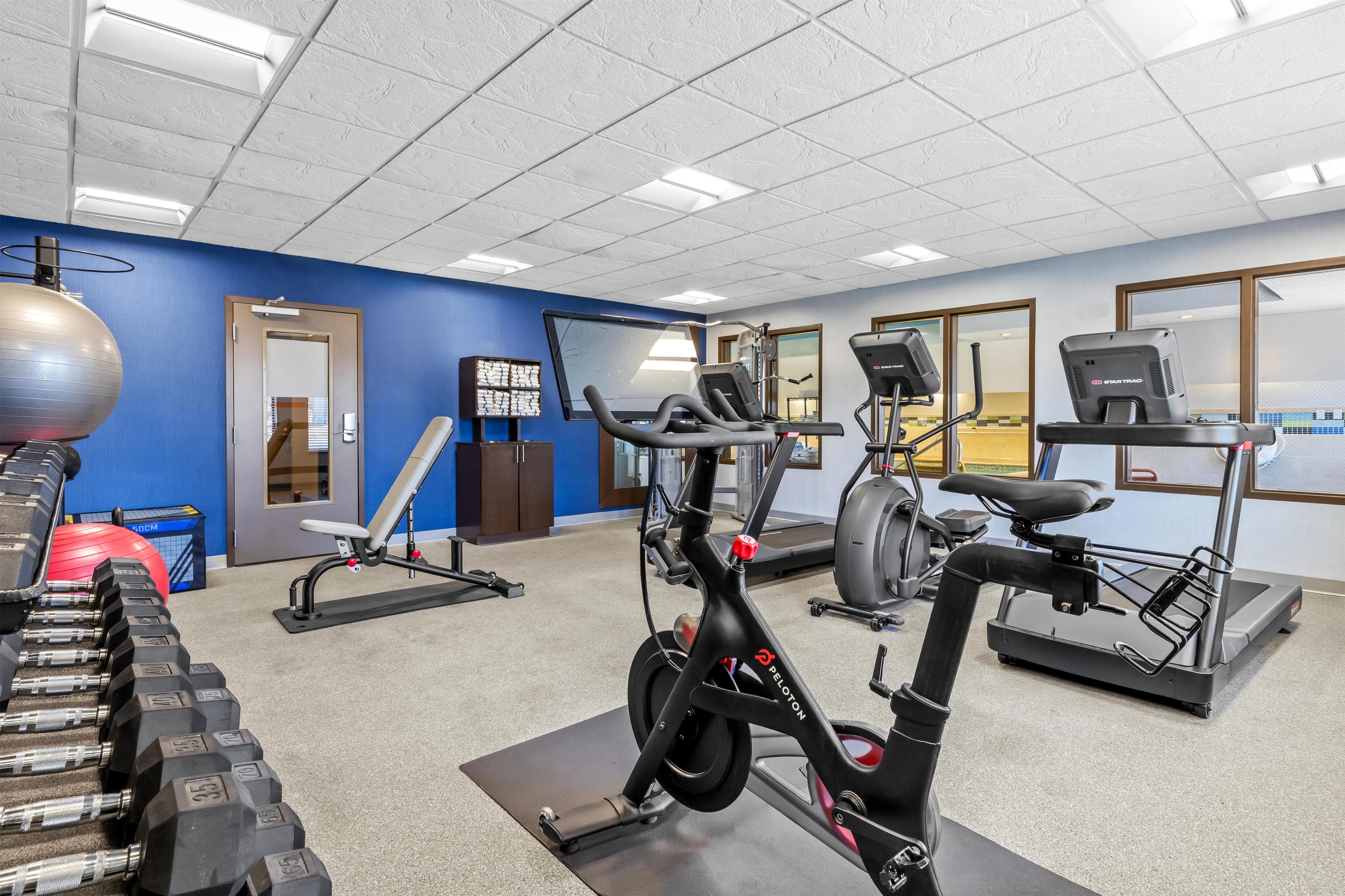 A gym with exercise equipment, a blue wall, and a door.