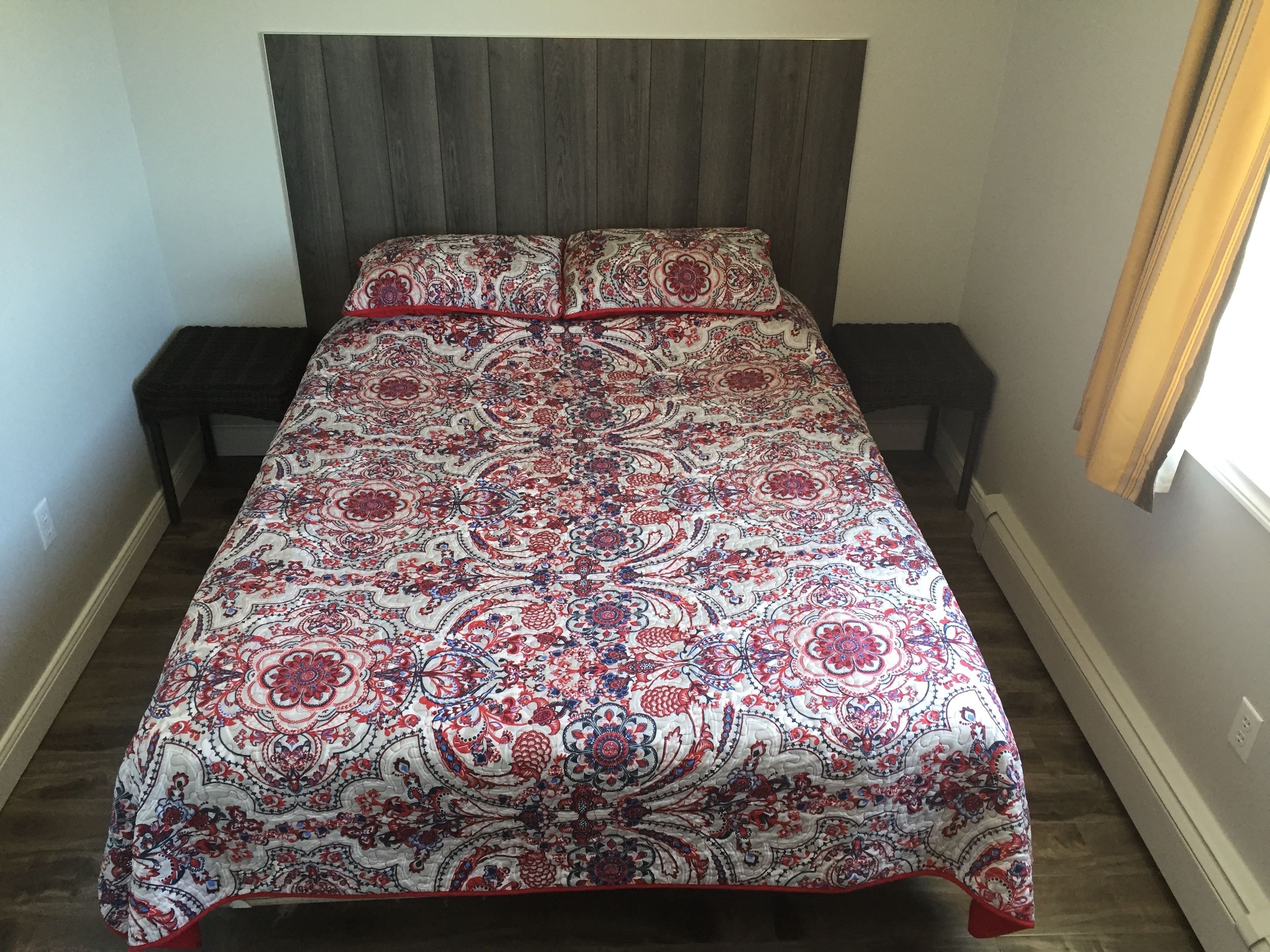 A bed with a patterned bedspread, two bedside tables, and a headboard.