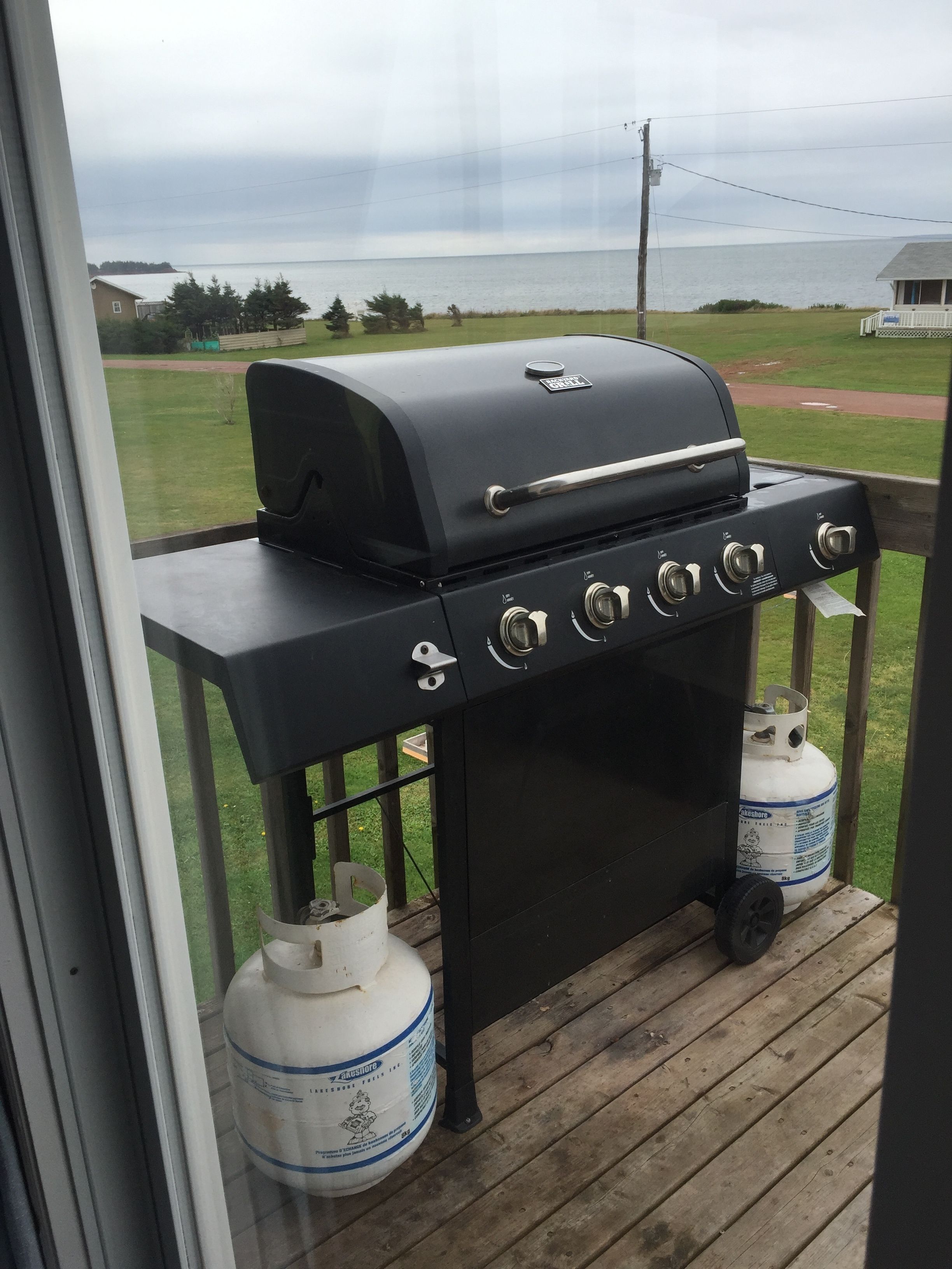 Una parrilla para barbacoa en una terraza de madera con vista al océano.
