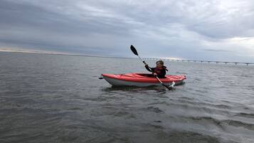 Una persona haciendo kayak sobre aguas tranquilas, bajo un cielo nublado.