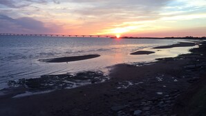 A sunset over a river with a bridge in the distance.