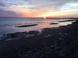 A sunset over a river with a bridge in the distance.